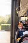 Женщина пригородная с помощью мобильного телефона во время путешествия в современном автобусе — стоковое фото