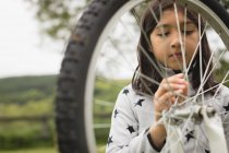 Молода дівчина ремонтує велосипед — стокове фото