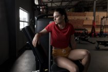 Thoughtful woman relaxing in fitness studio — Stock Photo