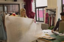 Дизайнер одежды проверяет ткань в ателье моды — стоковое фото