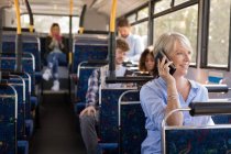 Жінка-комісар розмовляє по мобільному телефону під час подорожі в сучасному автобусі — стокове фото