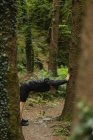 Jovem fazendo alongamento na floresta — Fotografia de Stock