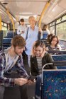 Junges Paar benutzt Handy während der Fahrt in modernem Bus — Stockfoto