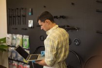 Hombre atento usando el ordenador portátil en el taller - foto de stock