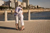 Coppia di anziani che si abbracciano vicino al mare sul lungomare — Foto stock