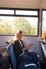 Жінка слухає музику під час подорожі в сучасному автобусі — стокове фото