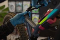 Primer plano de la bicicleta de reparación del hombre en el taller - foto de stock