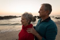 Крупный план пожилой пары, стоящей на пляже на закате — стоковое фото