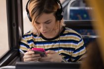 Frau hört während der Fahrt im modernen Bus Musik — Stockfoto
