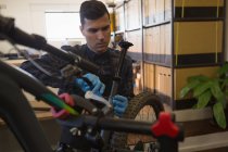Внимательный человек ремонтирует велосипед в мастерской — стоковое фото