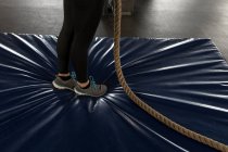 Low section of woman doing rope climbing exercise in fitness gym — Stock Photo