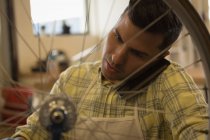 Nahaufnahme eines Mannes, der während der Reparatur eines Fahrrads in der Werkstatt mit dem Handy telefoniert — Stockfoto