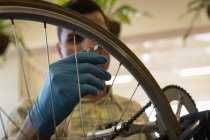 Close-up of man fixing bicycle wheel strings in workshop — Stock Photo