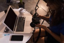 Modèle féminin regardant appareil photo numérique en studio photo — Photo de stock