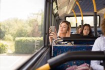 Viajero femenino tomando selfie en el teléfono móvil mientras viaja en autobús moderno - foto de stock