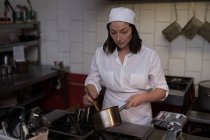 Schöne Bäckerin bereitet Essen in der Küche beim Bäcker zu — Stockfoto