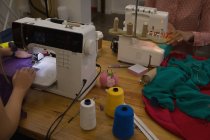 Primer plano del diseñador de moda utilizando la máquina de coser en el estudio de moda - foto de stock