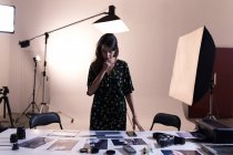 Fotógrafa feminina olhando para fotografias em estúdio de fotografia — Fotografia de Stock