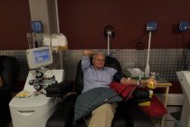 Active senior man donating blood in blood bank — Stock Photo