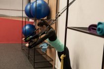 Молодая женщина делает упражнения с подвесным кабелем в фитнес-студии — стоковое фото