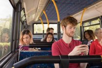 Comutador masculino inteligente usando telefone celular enquanto viaja em ônibus moderno — Fotografia de Stock