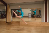 Красивая балерина танцует перед зеркалом в танцевальной студии — стоковое фото