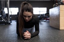Красивая женщина делает упражнения на доске в фитнес-студии — стоковое фото