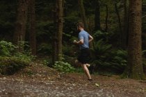 Giovane uomo che fa jogging sul sentiero forestale — Foto stock