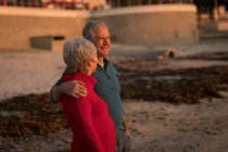 Casal sênior conversando na praia durante o pôr do sol — Fotografia de Stock