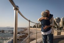 Seniorenpaar umarmt sich an einem sonnigen Tag an der Strandpromenade — Stockfoto