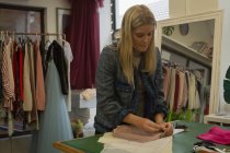 Beautiful fashion designer pinning on fabric in fashion studio — Stock Photo
