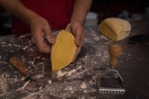 Boulanger montrant morceau de pâte à découper dans la boulangerie — Photo de stock