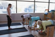 Treinador instruindo grupo de mulheres idosas no centro de ioga — Fotografia de Stock