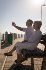 Glückliches Senioren-Paar macht Fotos vom Handy an der Promenade — Stockfoto
