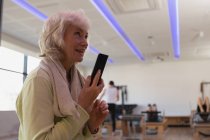 Senior woman talking on mobile phone in yoga center — Stock Photo