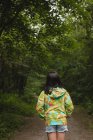 Giovane ragazza in piedi da sola nel sentiero della foresta — Foto stock