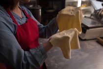 Baker segurando uma massa enrolada em uma mão na padaria — Fotografia de Stock