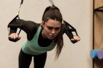 Young woman doing exercise with suspension cable in fitness studio — Stock Photo