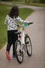 Вид сзади девушки, идущей на велосипеде по улице — стоковое фото
