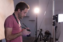 Male photographer reviewing photos on digital camera in photo studio — Stock Photo