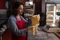 Женщина-пекарь держит макароны в руке в пекарне — стоковое фото