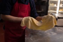 Baker holding rolled handmade pasta in a bakery — Stock Photo