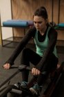 Jeune femme faisant de l'exercice sur rameur dans un studio de fitness — Photo de stock