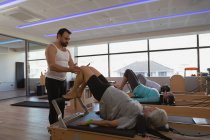 Trainer, der eine Gruppe älterer Frauen unterrichtet, während er Yoga im Yogazentrum durchführt — Stockfoto