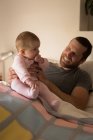 Father having fun with baby on bed in bedroom at home — Stock Photo
