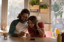 Счастливая пара, использующая мобильный телефон в кафе — стоковое фото