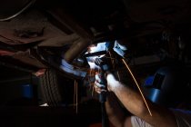 Mecânico masculino usando tocha flamejante na garagem — Fotografia de Stock