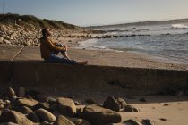Nachdenklicher Mann sitzt auf Strandpromenade — Stockfoto