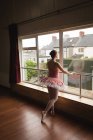 Вид ззаду балерини, який дивиться через вікно в танцювальній студії — стокове фото