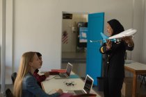 Piloto femenino enseñando sobre avión modelo a niños en instituto de entrenamiento - foto de stock